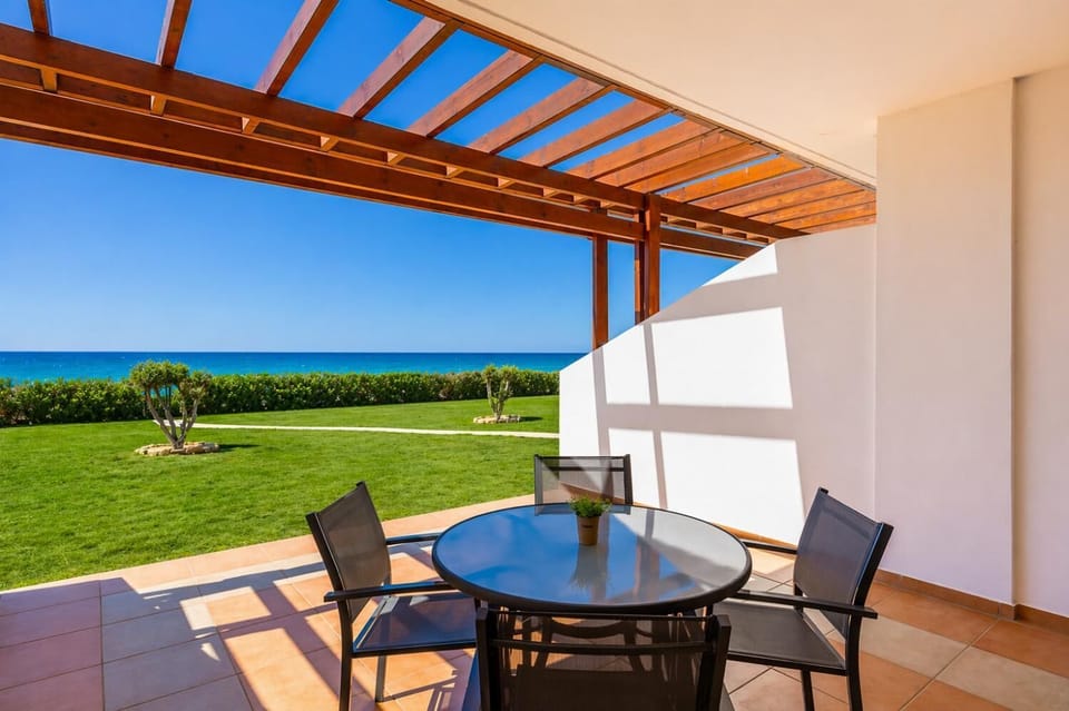 A ground-level perspective from the shaded patio, emphasizing the seamless connection between the villa's outdoor living space and the beachfront garden.