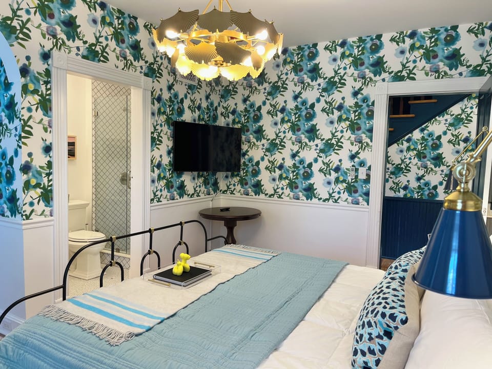 Suite 1: Private entrance with semi-private porch or additional optional entry through hallway, King Anthropologie bed, 50" Smart TV, porcelain tile bath, and option to adjoin with Suite 2. 