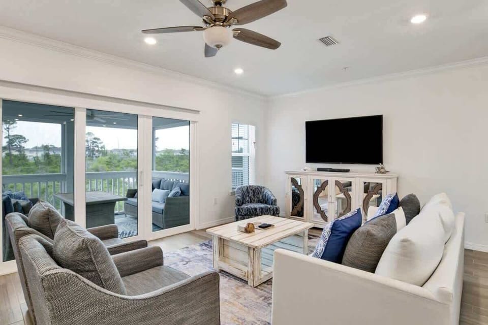 Spacious living room featuring ample seating, a smart TV, and access to a screened-in patio for relaxed gatherings.