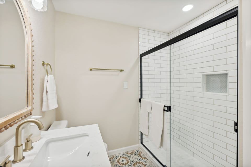 Fully remodeled bathroom with large walk-in shower, stone countertop and tile floors.