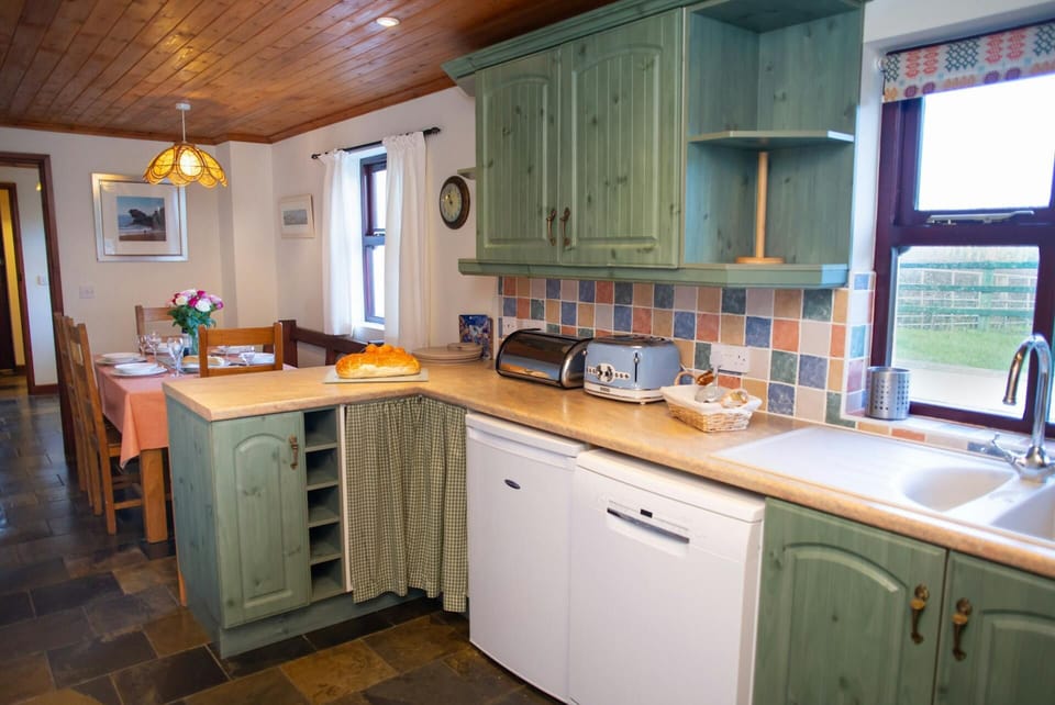 Kitchen with dishwasher, fridge and toaster, dining table with chairs