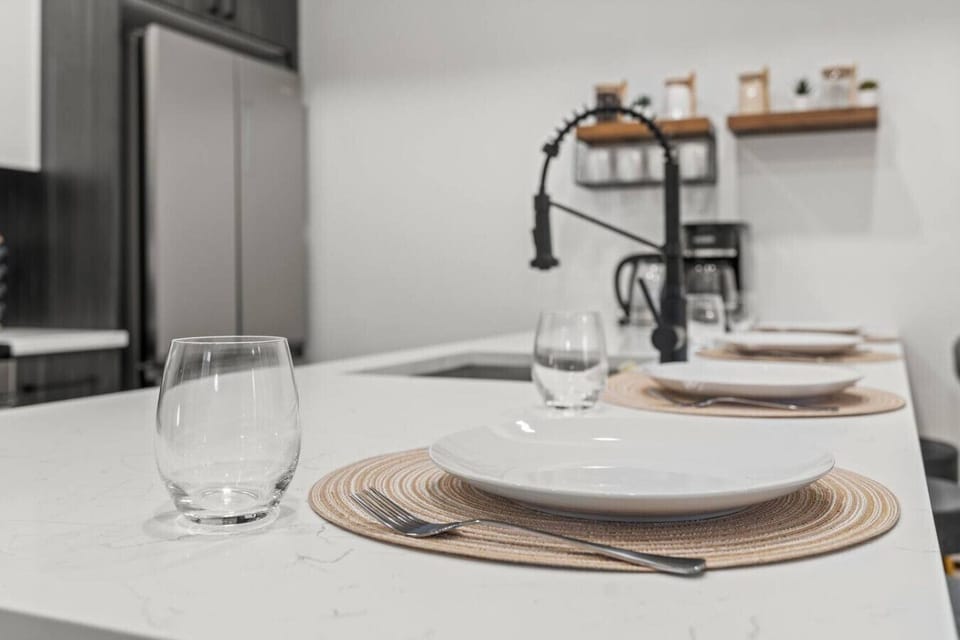 Elegant kitchen island setup with modern place settings and sleek fixtures, perfect for dining or entertaining.