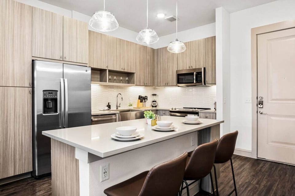 Prepare meals in this modern, fully-equipped kitchen featuring stainless steel appliances and a spacious island with bar seating. The open layout makes it easy to cook and entertain, ensuring a delightful culinary experience during your stay.