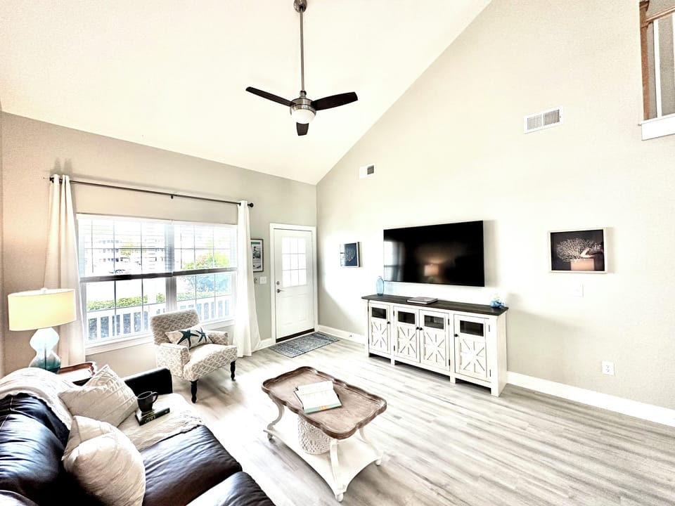 Spacious living room with TV, leather couch, arm chair, board games