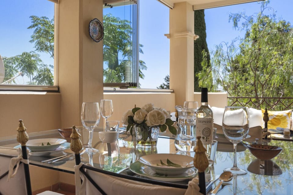 Sunny terrace with chillout seating area, dining area, Lumon glazing, and partial sea views