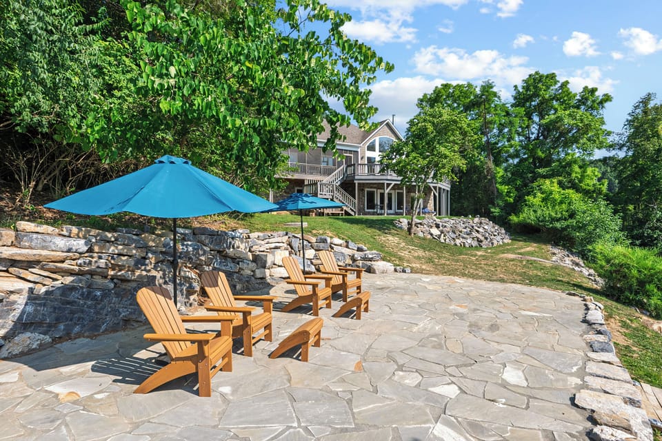 Lakeside stone patio with Adirondack chairs & umbrellas