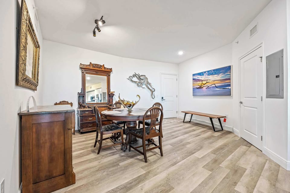 Dining area with antique wooden furniture and coastal artwork for a relaxed atmosphere.