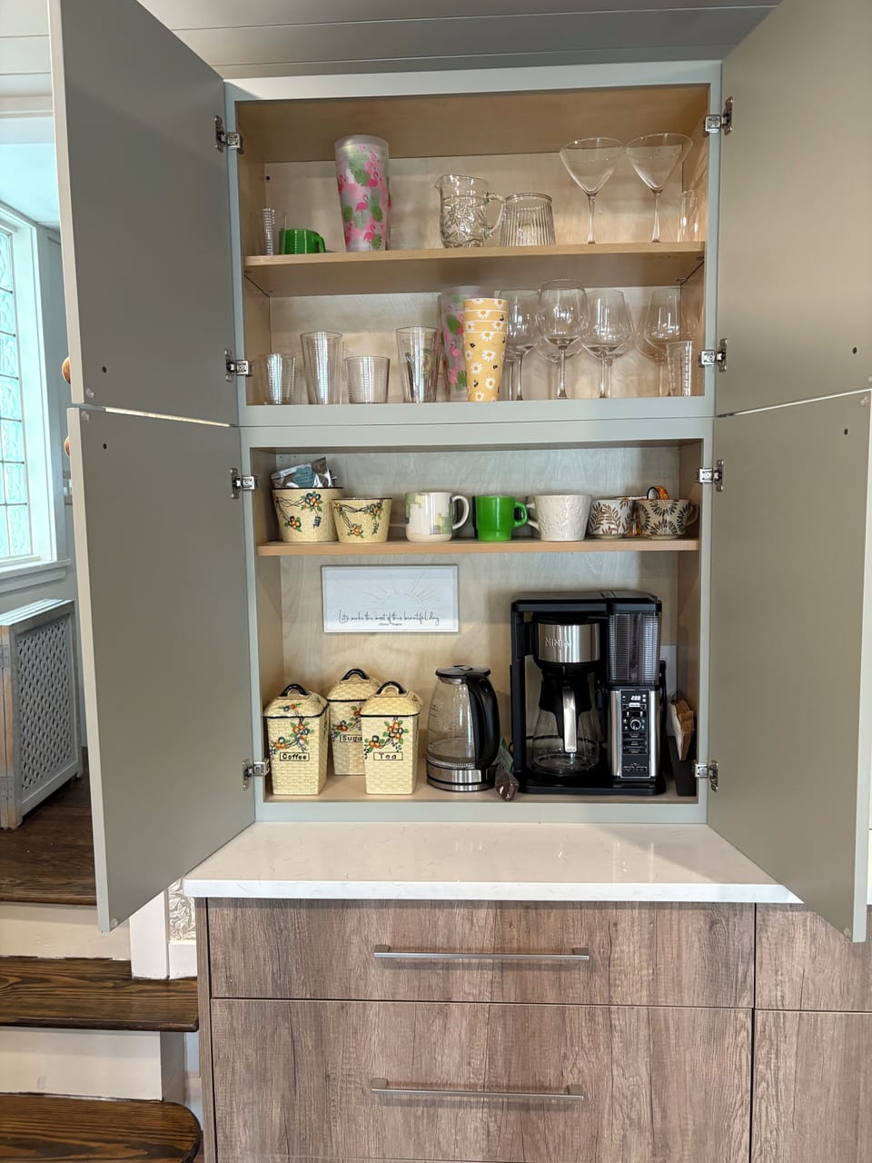 Hutch houses coffee maker, tea kettle, microwave, glassware and serving pieces..