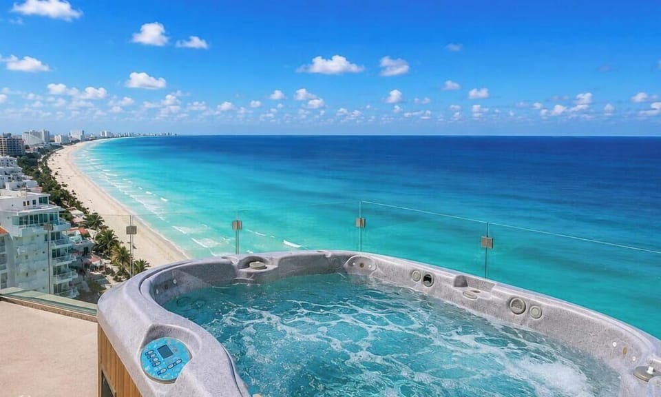#313 - Penthouse Combo - 8 bedrooms, 6 baths sleeps 18 Top-floor hot tub with bubbling water overlooks the turquoise ocean and white sandy beach under a bright blue sky.