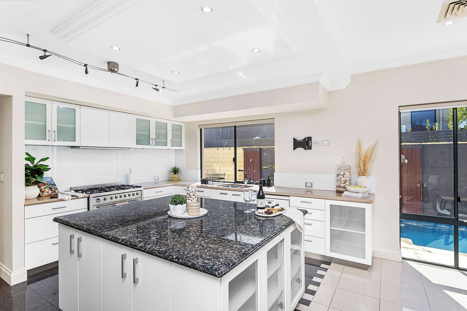 The open layout connects dining, living, and a sleek kitchen with pool views.