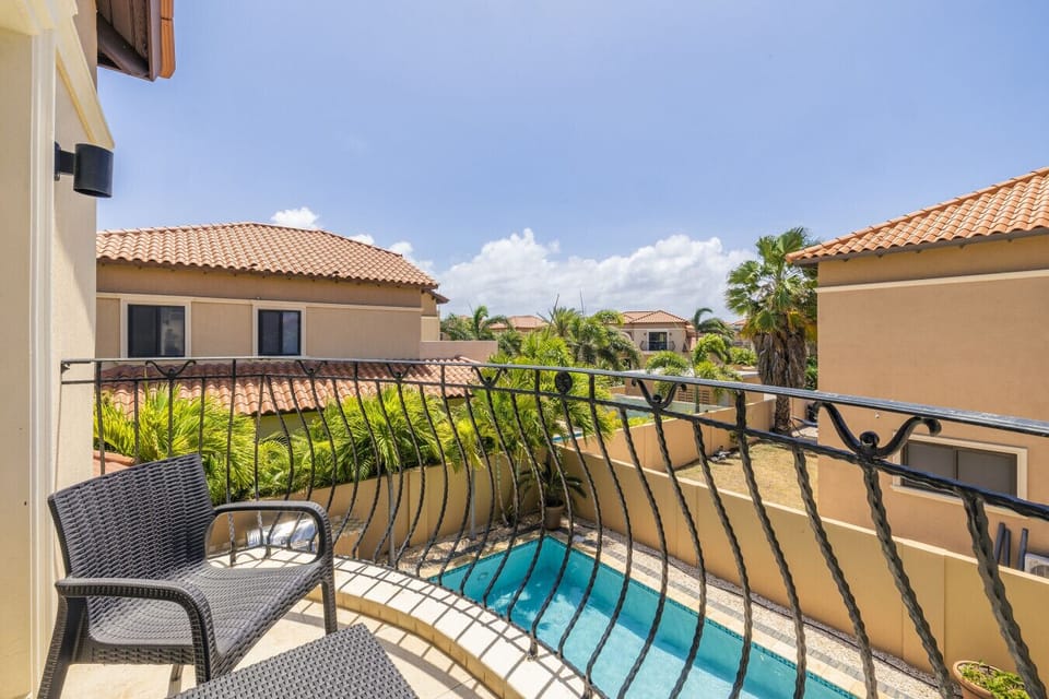 Take in the beautiful view from this private balcony, overlooking the serene pool and lush greenery. Perfect for relaxing and enjoying the sunny weather in a peaceful, cozy setting.
