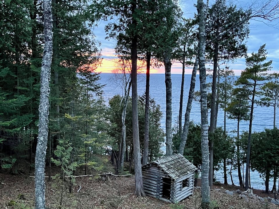 Historic log cabin playhouse with sunset