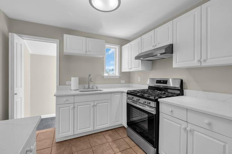 New white speckled quartz counters and stainless steel stove.
