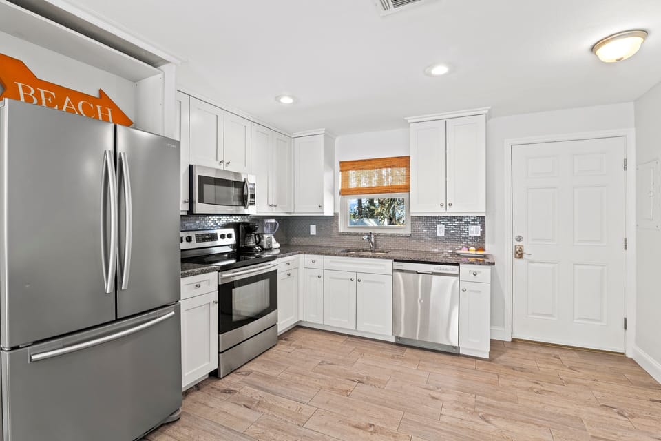 Kitchen full angle displaying all major appliances and main entrance