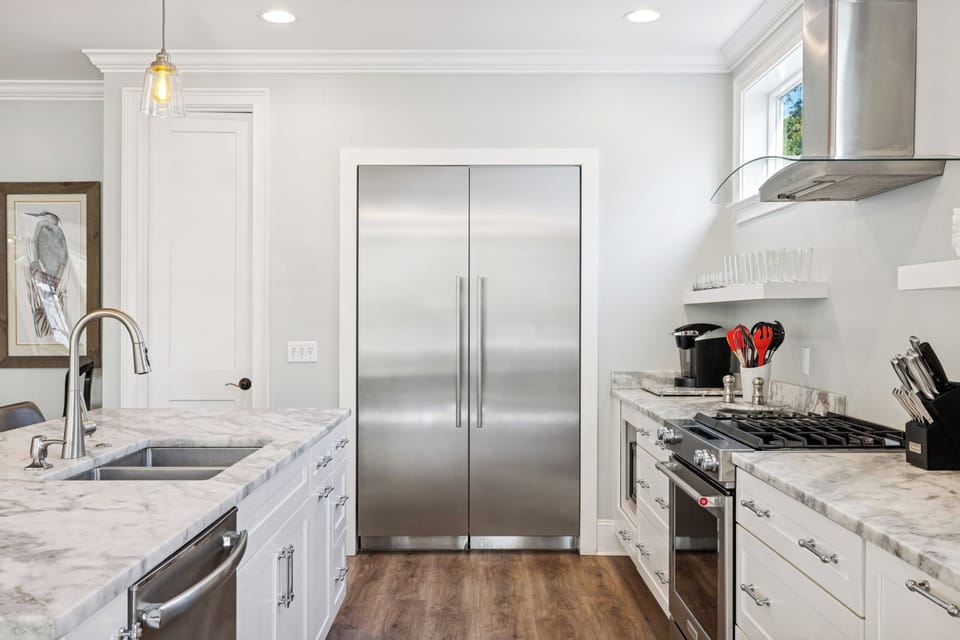 A fully stocked kitchen with stainless steel appliances, and 4 barstools for extra seating.
