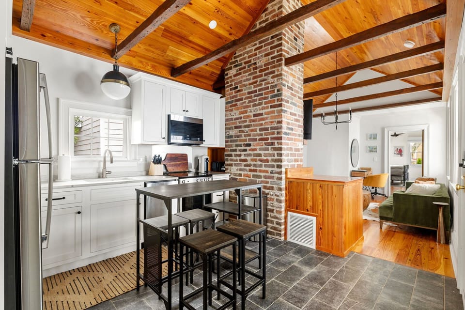 An open kitchen with a view into the living room, separated by a charming brick fireplace that adds warmth and character to the home.