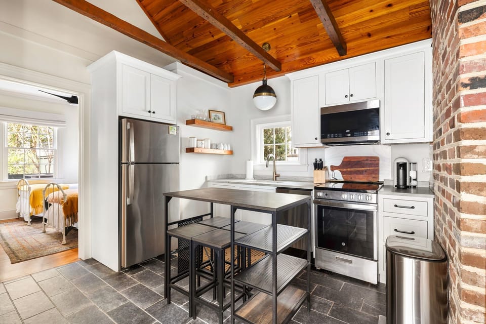 A chef’s dream kitchen with vaulted, beamed ceilings that echo the charm of the home’s historic roots. Stainless steel appliances make cooking a breeze, and the island bar with seating is perfect for casual meals or gathering with friends
