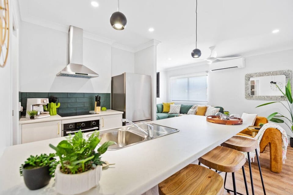 The modern kitchen is fully equipped with brand-new appliances, sleek cabinetry, and plenty of counter space. It includes a dishwasher, oven, and large fridge, offering a stylish and functional space for cooking and entertaining in comfort.