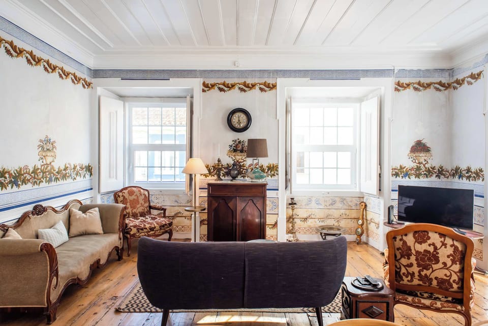 Santo Antonio 1 spacious living area with large windows, showcasing a blend of antique and modern furniture.