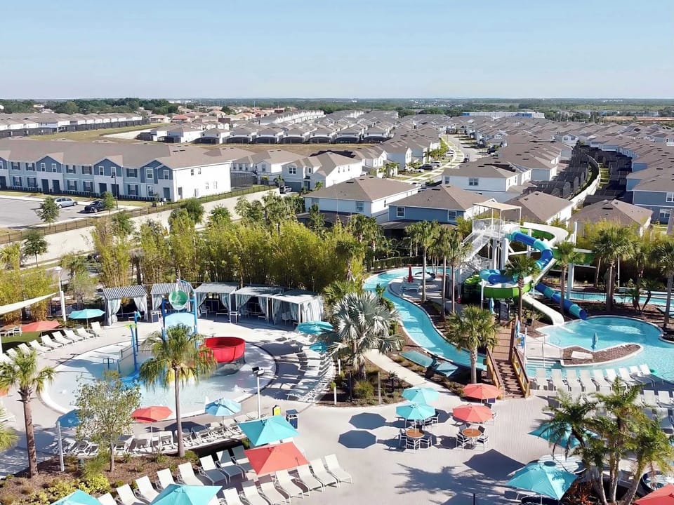 Resort clubhouse featuring a lazy river, waterslide, large pool, relaxing jacuzzi, and plenty of lounge seating for the perfect Florida vacation day.