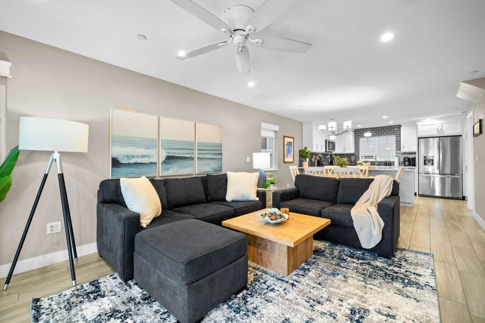 Spacious living room with plush sectional, ocean art, and open flow to the kitchen. 🛋️🌊🍽️