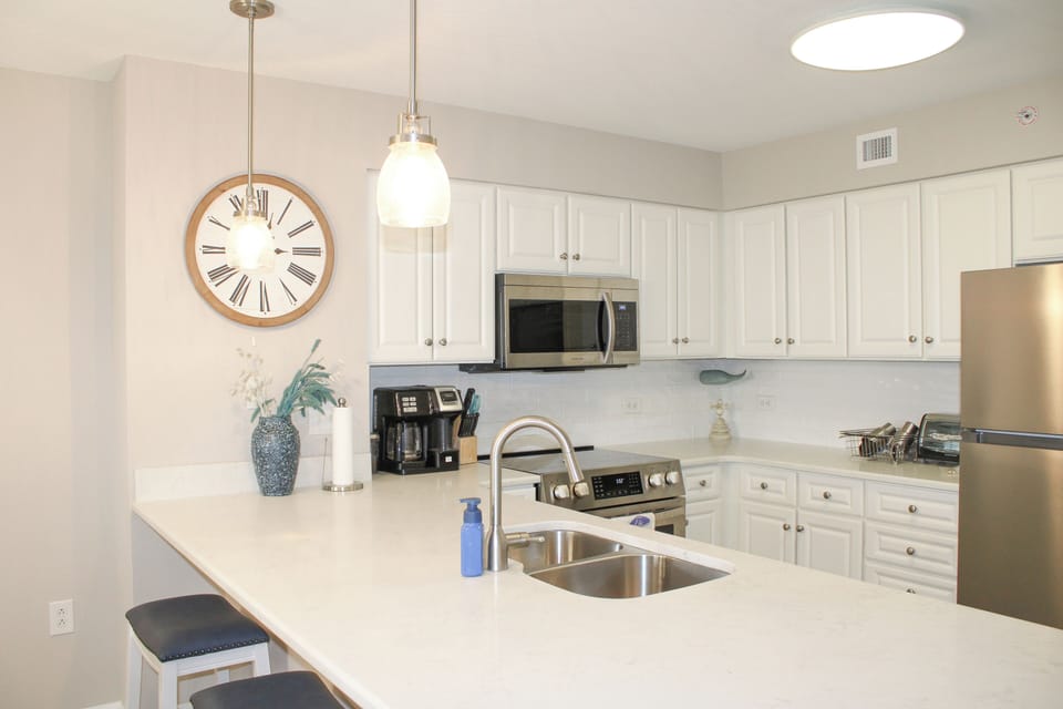 Cook your favorite meals in this bright, fully-equipped kitchen with modern appliances, granite counters, and stylish pendant lighting.