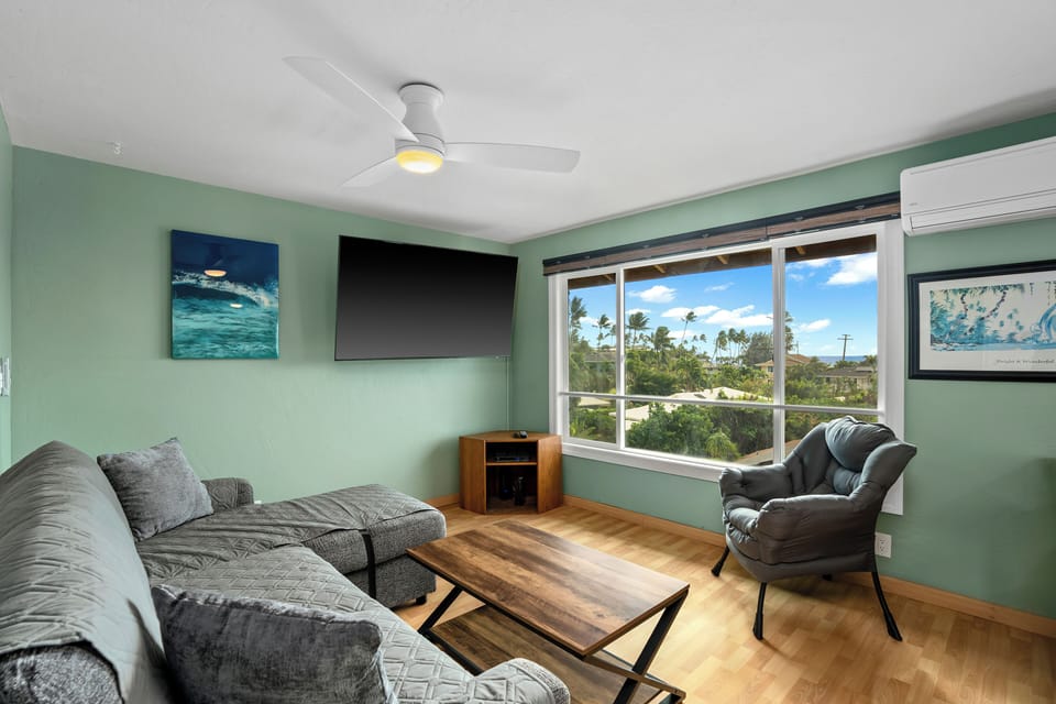 Relax in your bright, coastal-inspired living room with calming ocean views and tropical breezes. Unwind on the comfy sofa, enjoy the ceiling fan, and feel right at home with modern amenities and island charm.