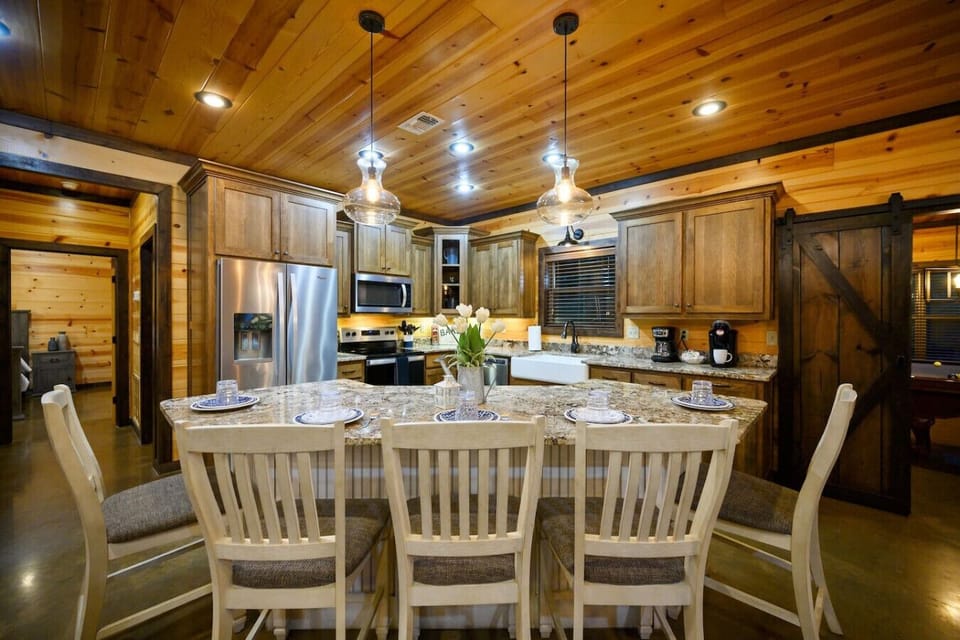 This granite island stretches out like the ultimate gathering spot, with those pendant lights hanging overhead and the whole kitchen flowing naturally behind it—perfect for when everyone wants to hang out in the same place.