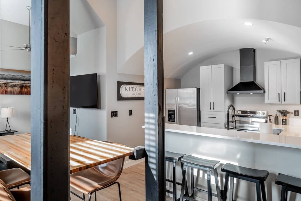 View looking through the original beams into the kitchen, dining area and living space. Nice, high ceilings and large windows allow for ample sunlight