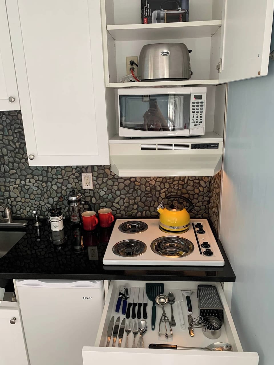 The kitchenette is stocked with pans and utensils for a simple meal.
