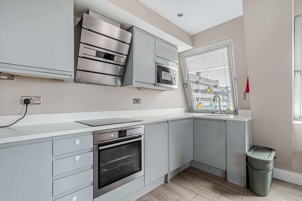 Well-equipped modern kitchen with sleek grey cabinetry, integrated appliances, and bright natural lighting highlighting white countertops 