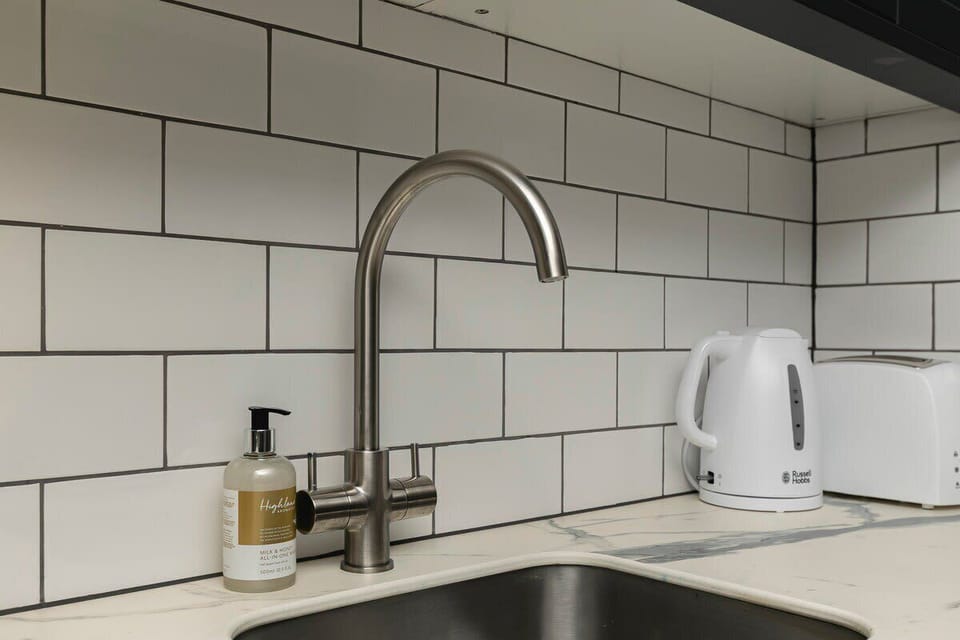 Sink area with white kettle and soap dispenser