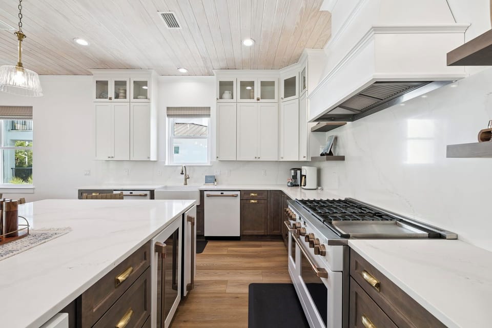 Step into your gourmet kitchen, where elegant white cabinetry meets warm wood tones beneath a stunning plank ceiling. Cook your favorite meals on a professional-grade gas range with ample counter space for prep.