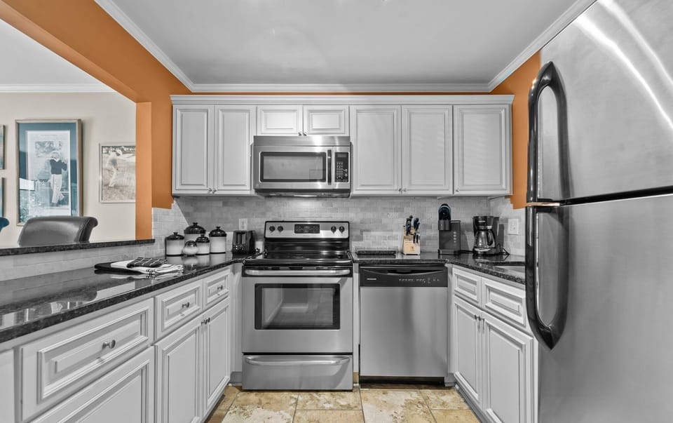 Fully equipped kitchen with fridge, stove, dishwasher, coffee maker.