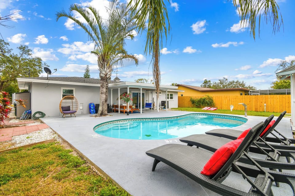 Luxury Largo pool home near Indian rocks Beach with heated swimming pool, premium outdoor loungers, and private fence yard. Modern Florida vacation rental featuring tropical landscaping and contemporary outdoor furnishings, perfect for family getaway