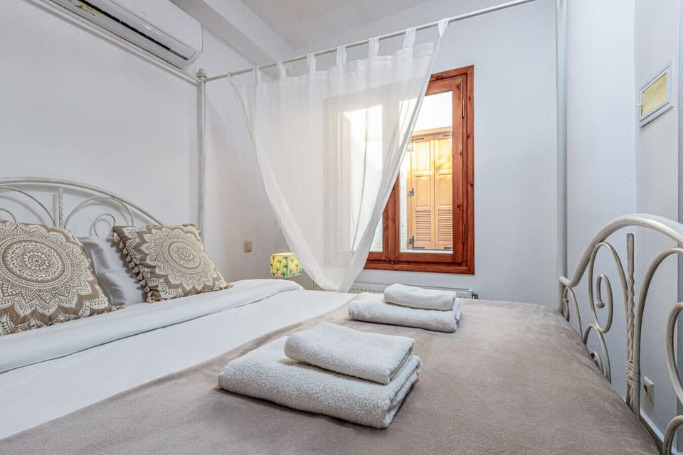 The bedroom of Casa Eleni offers a cozy retreat with a queen-sized bed, a comfortable sofa, and a smart TV for entertainment. It also features an ensuite bathroom with a bathtub, providing comfort and relaxation.