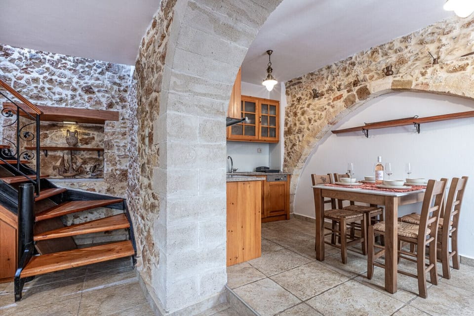 The kitchen of Casa Eleni features a fully equipped cooking space, a refrigerator, and a dining table with four seats, offering both functionality and comfort.