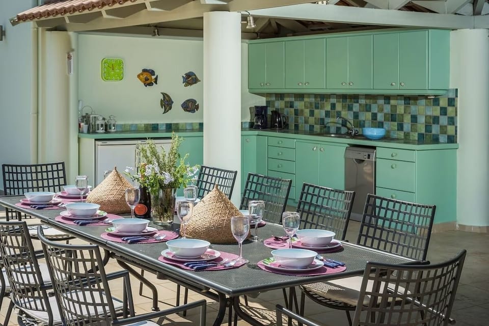 a very well equipped pool side kitchen with a large dining table,