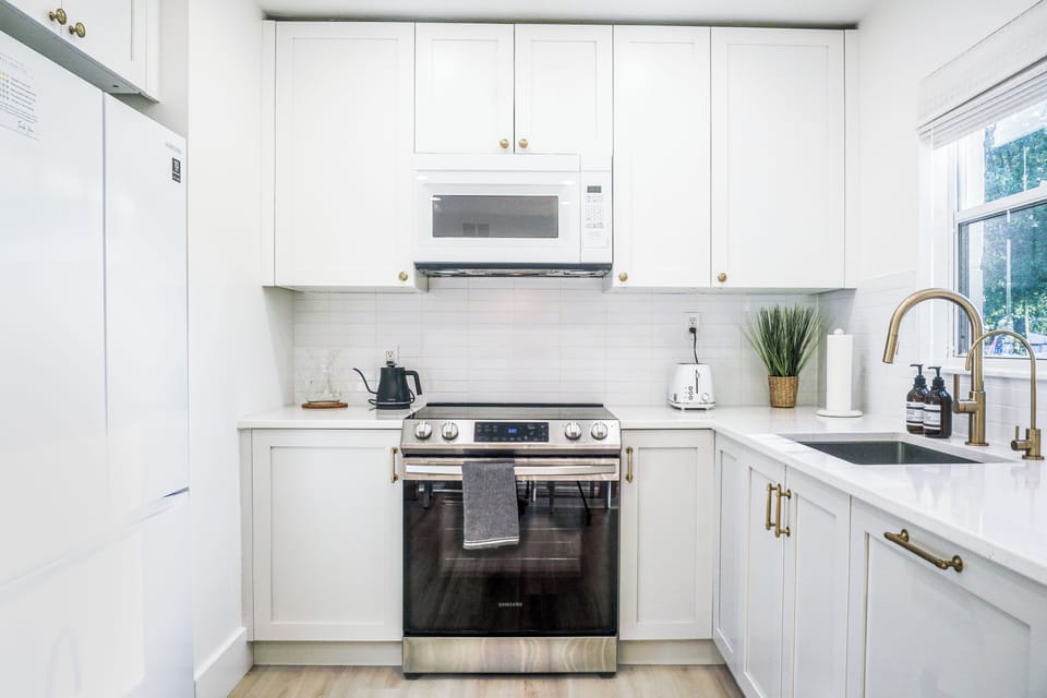 Sleek white fridge, microwave, toaster, range, dishwasher disguised as cabinet