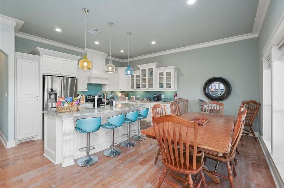 Open dining and kitchen area with seating for large groups, breakfast bar, and modern coastal decor near Crystal Beach.