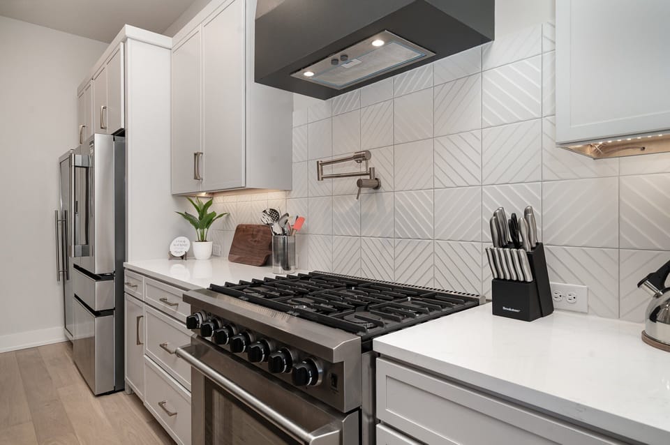 The fully open floor-equipped modern kitchen is stocked with all culinary essentials, stainless steel appliances, a wine fridge, and breakfast bar seating. (2nd Floor)