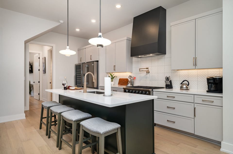 The fully open floor-equipped modern kitchen is stocked with all culinary essentials, stainless steel appliances, a wine fridge, and breakfast bar seating. (2nd Floor)