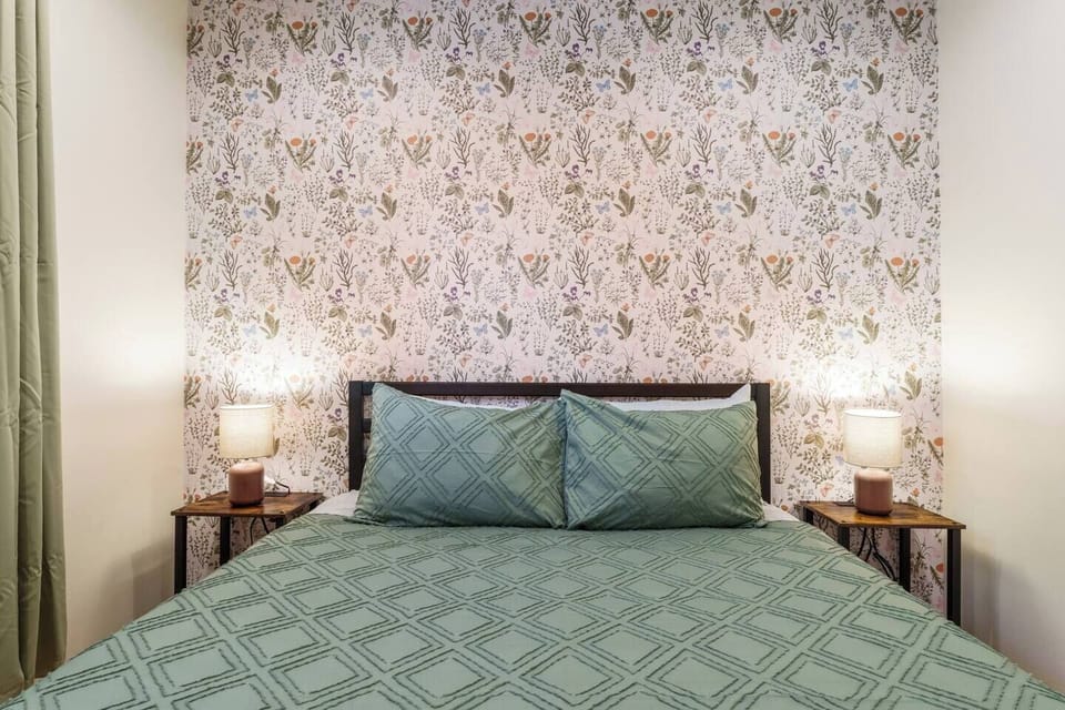 Cozy bedroom with queen bed, soft lighting, and elegant floral accent wall