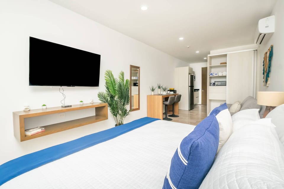 Modern bedroom with a large Smart TV & comfortable bed.