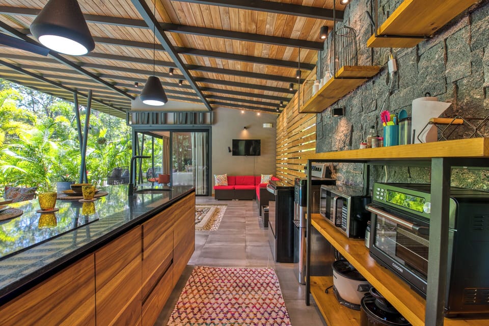 Fully stocked open air kitchen overlooks pool and gardens.