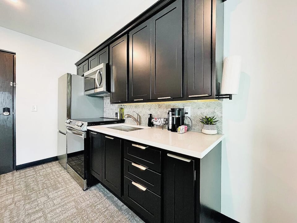 Fully equipped kitchen with elegant black cabinetry, stainless steel appliances, and all essentials provided for a seamless cooking experience.





A modern kitchen equipped with stainless steel appliances, dark cabinetry, and a spacious countertop perfect for meal prep. Complemented by stylish decor, this kitchen is both functional and inviting for your culinary adventures.
