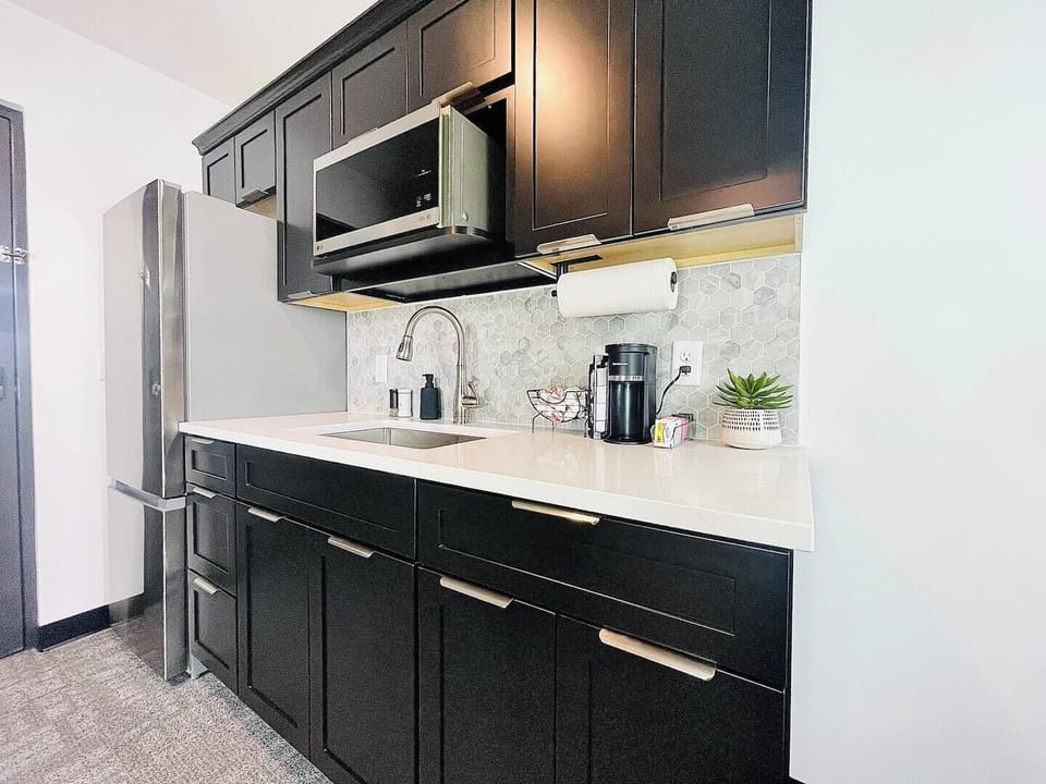 Stylish kitchen with dark cabinetry, stainless steel appliances, and a well-appointed coffee station for your morning needs.