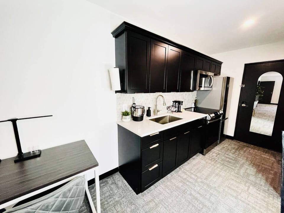 Stylish kitchen with dark cabinetry, stainless steel appliances, and a well-appointed coffee station for your morning needs.