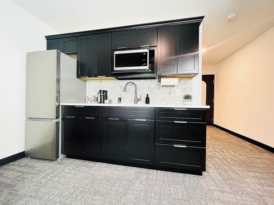 Stylish kitchen with dark cabinetry, stainless steel appliances, and a well-appointed coffee station for your morning needs.


