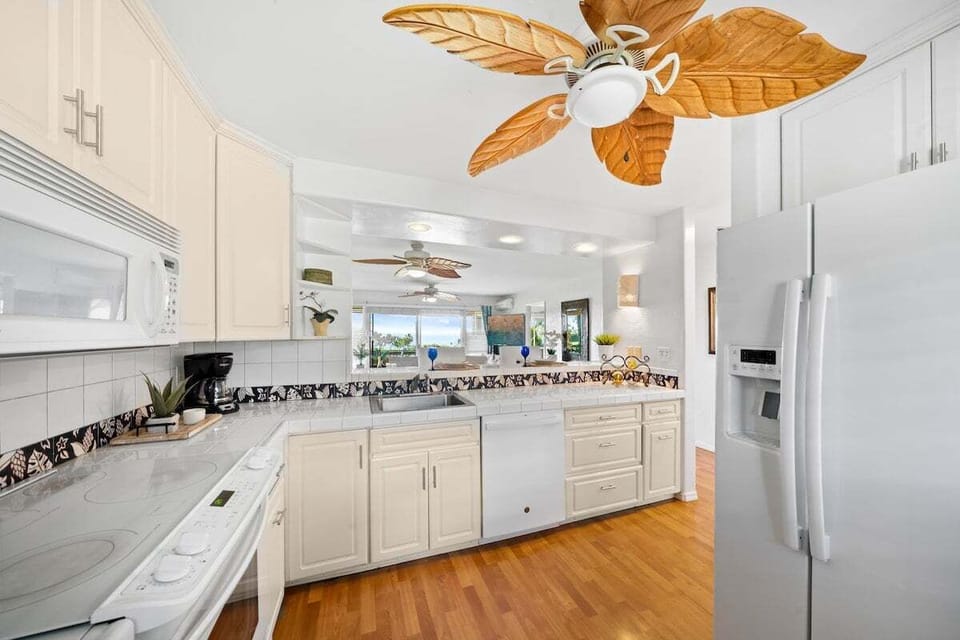 Spacious and clean kitchen complete with white cabinets and matching white appliances.